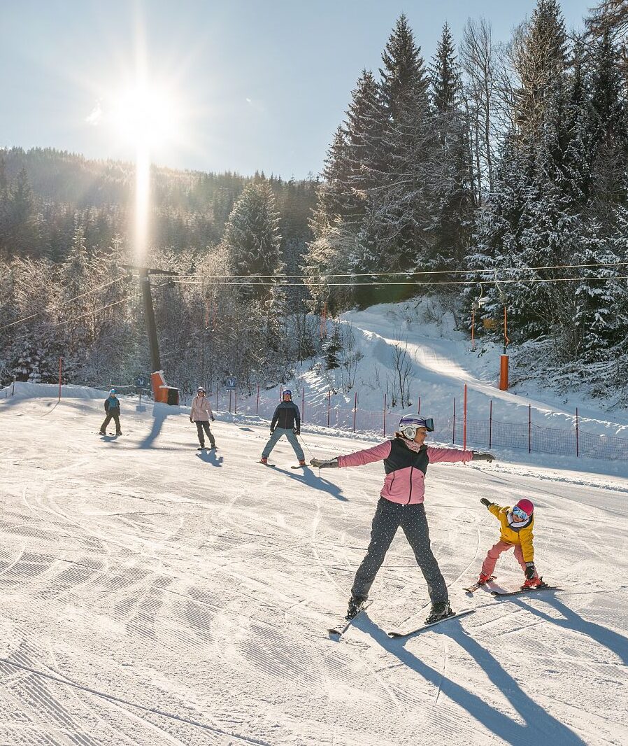 Familien vom Gut Weissenhof beim Skifahren auf der sonnigen Piste Schischaukel Radstadt-Altenmarkt im Salzburger Land