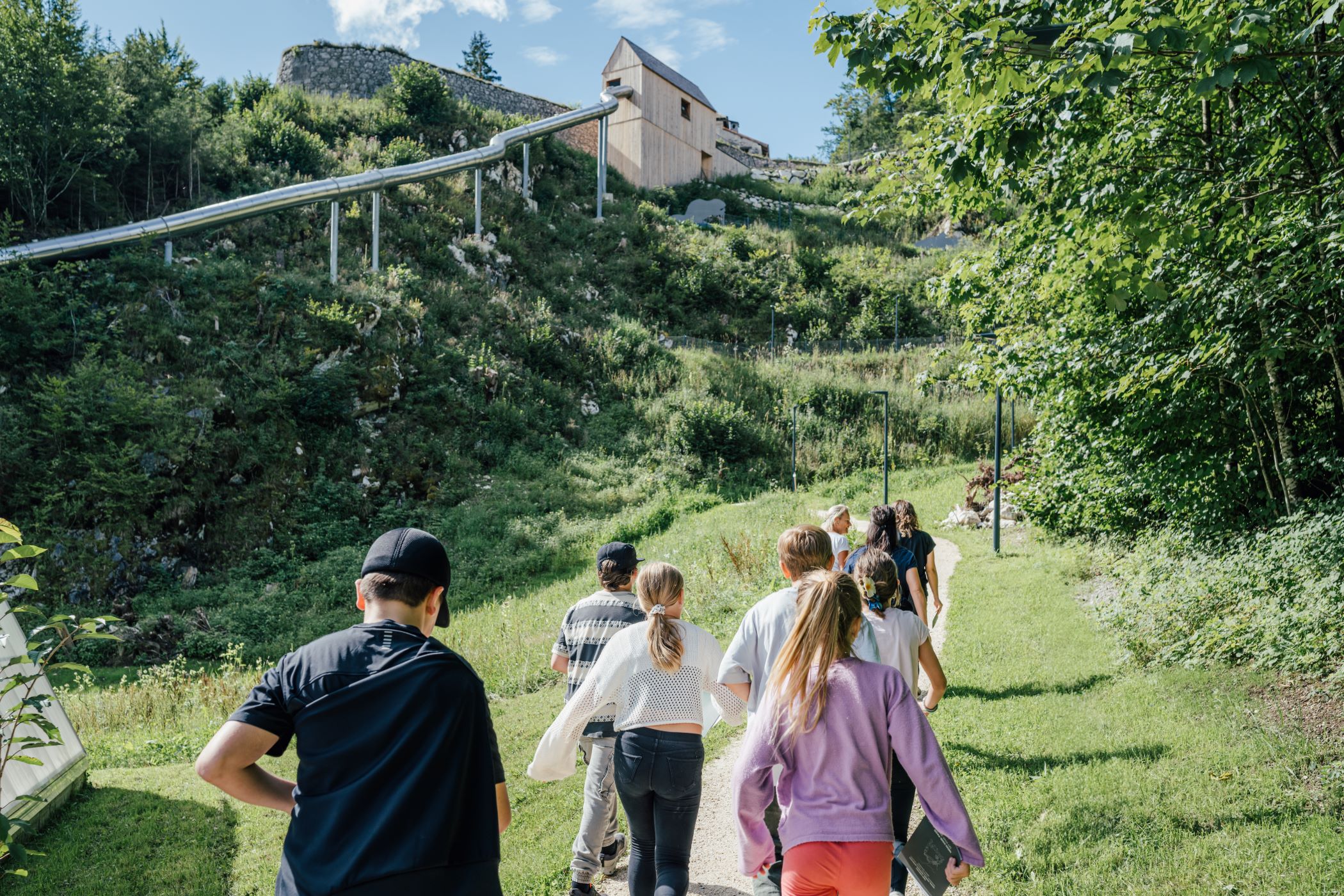 Kinder erkunden den Fort Kniepass auf einem Wanderweg durch grüne Landschaft im Salzburger Land